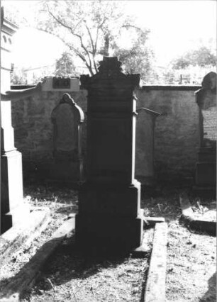 Grabstein 40 (Index: 100105706) Material: Sandstein Zustand: stärker verwittert, Sockel gespalten Maße HxBxT: 176x59x38 cm Beschreibung: Stele, getreppter und profilierter Sockel, Dach mit Volutenaufsatz und Akroteren, Schriftfeld eingetieft: Grabstein 40