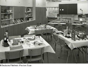 Anbauwand : Ausstellungskoje mit Polytechnischem Kabinett. Ansicht mit Anbauwand und Schulbänken (1973) mit gebastelten Exponaten