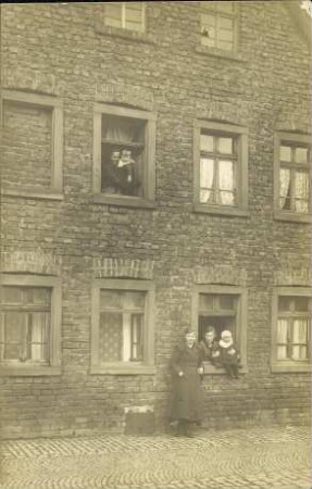 [Familie schaut aus Hausfenstern]