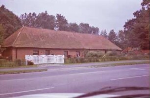 Blumendorf: "Lange Kate": Mehrfamilienkate aus Backstein mit Ziegeldach: traufständige Straßenfront mit Sprossenfenstern, Eingangstüren: davor Einfahrt, Holztor