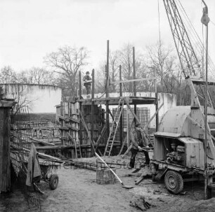 Abwasser: Klärwerk: Wöhrendamm: 3. Bauabschnitt: Bau des Belebungsbeckens, des Schlammstabilisierungsbeckens und des Nachklärbeckens: Baugrube und verschalte Beckenteile: rechts Arbeiter an Bagger: links Schubkarre mit Jacke: hinten Mitte Arbeiter auf Gerüst: dahinter zwei Klärbecken: im Hintergrund Bäume