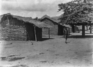 Ehemalige Missionssiedlung : Ehemalige Missionssiedlung aus Hütten am Ufer des Rio Pilcomayo. Im Vordergrund ein Mann der Toba.