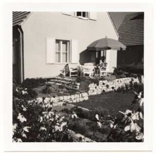 Garten Fröhlich, Kleinmachnow: Terrasse mit Mauer und Stufen sowie Frau auf Stuhl