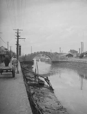 Steinerne Bogenbrücke über eine Wasserstraße in Sakaide : Blick von der Uferstraße