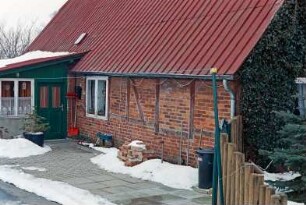 Hauptstraße 44: Bauernhaus aus Fachwerk: Traufseite, hinten Auslucht mit Eingangstür, davor Plattenweg: rechts Giebelseite Wohntrakt, mit Kletterpflanzen [angeschnitten]: vorne Holzzaun