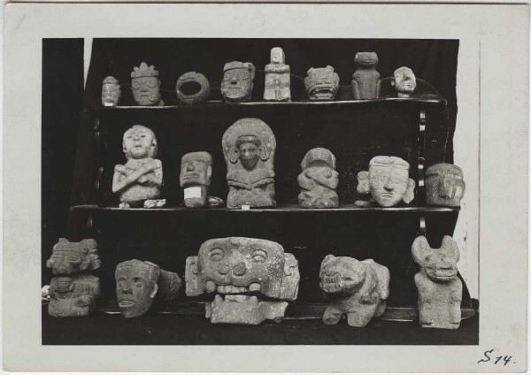 Steinköpfe und -figuren darunter Tlaloc-Gesichter aus der Slg. Sologuren