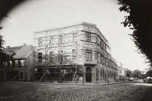 Eingerüstetes Wohnhaus mit Laden