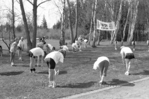 Lauftreff Reinfeld: Trimm-Trab: Badeanstalt: Liegewiese: Teilnehmer im Kreis bei Dehnübungen: hinten Banner und Bäume
