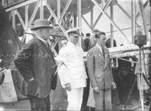 Kapitän Leopold Ziegenbein mit James Fitzmaurice und einer dritten Person an Bord des Hochseepassagierdampfers "Bremen", rechts die Katapultanlage für das Postflugzeug