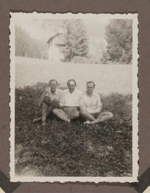 Heinrich Zimmer sitzt mit zwei jungen Männern auf einer Wiese