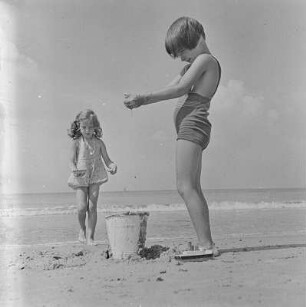 Zwei Kinder spielen mit Sand am Strand