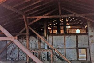 Am Markt (10): traufständiges Backsteingebäude mit umlaufendem Gesims: Innenansicht: Dach mit dreifach stehendem Stuhl: Blick auf Firstpfette, Mittelpfette, Innenständer, Kehlbalken, Dachsparren: Innenwand mit Gefachen und Ausmauerung: hinten Giebelwand, Fenster: unten Holzboden