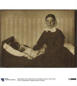 Kind im Bett und Frau mit Kopftuch
