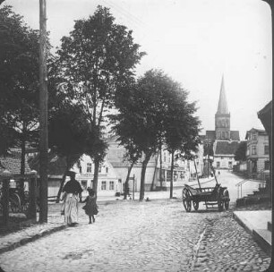 Bergen auf Rügen. Blick von der Marktstraße mit Passanten und Leiterwagen durch die Kirchstraße nach Osten zur Pfarrkirche St. Marien