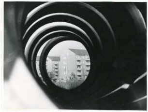 Blick durch Betonrohre auf Nachkriegs - Wohnblocks