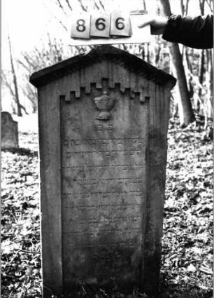 Grabstein 866 (Index: 99751225) Material: Sandstein Zustand: leicht verwittert Maße HxBxT: 113x56x13 cm Beschreibung: Stele, giebelartiger Abschluß mit Verdachung, Schriftfeld eingetieft Symbolik: Schale mit Deckel, Zahnfries Besonderheit: Zitat Proverbia 12, 4 und 31, 10: Grabstein 866