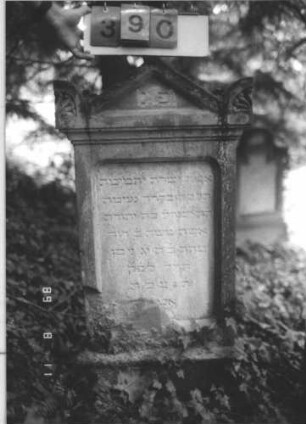 Grabstein 390 (Index: 99799650) Material: Sandstein Zustand: stark verwittert, unten angeschlagen und zementiert Maße HxBxT: 120x57x19 cm Beschreibung: Stele, Abdeckplatte, Giebelaufsatz, Seitenakrotere, Schriftfeld eingetieft, getreppter Sockel: Grabstein 390
