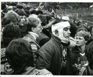 Fußballfan mit einbandagiertem Kopf im Stadion (Altersgruppe 18-21)