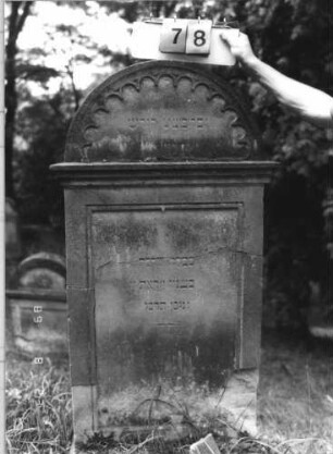 Grabstein 78 (Index: 100110806) Material: Sandstein Zustand: Giebel beschädigt, Abschieferungen an den unteren Ecken Maße HxBxT: 148x69x21 cm Beschreibung: Stele, Rundbogenabschluß mit Verdachung und Rundbogenfries, Schriftfelder eingetieft: Grabstein 78