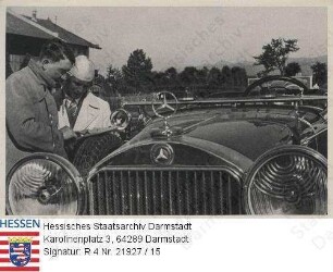 Hitler, Adolf (1889-1945) / Sammelwerk Nr. 15 'Adolf Hitler', Bild Nr. 15, Gruppe 67 / Porträt Adolf Hitlers, mit Fahrer vor Wagen stehend, eine Karte studierend, Halbfigur im Profil