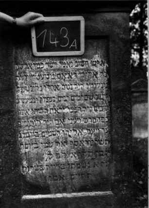 Grabstein 143 (Index: 100111292) Material: Sandstein Zustand: leicht verwittert Maße HxBxT: 167x79x20 cm Beschreibung: Stele, profilierter Sockel, Abdeckplatte mit Spitzbogenaufsatz mit Eckakroteren, rechteckiges Schriftfeld eingetieft Symbolik: Blüte, Blätter: Grabstein 143A