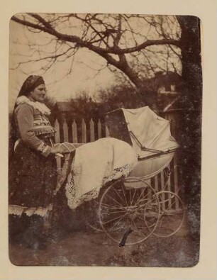 Frau in Tracht schiebt einen Kinderwagen, in dem wohl Franz von Hofmannsthal als Baby liegt