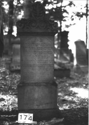 Grabstein 174 (Index: 99899033) Material: Sandstein Zustand: teilweise verwittert Maße HxBxT: 140x48x22 cm Beschreibung: augesockelte Stele, Aufsatz mit stilisierter Mittelpalmette, Voluten und Blüten Symbolik: Palmette, Voluten, Blüten: Grabstein 174
