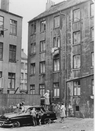 Hamburg-St. Pauli. Hinterhof in der Talstraße. Kinder spielen an einem Autowrack.