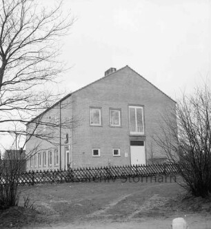 Fernmeldeamt: vorn Grünanlage und Jägerzaun: rechts und links Büsche: hinten links Gebäude