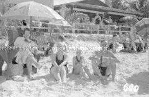 Touristen am Strand unter Sonnenschirmen