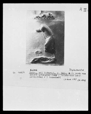 Mittleres Westportal — Südlicher Türpfosten — Gebeugte männliche Figur (Monat Dezember?), a 2