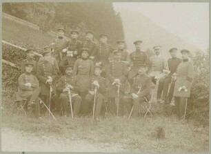 18 Offiziere auf dem Truppenübungsplatz Münsingen, teils stehend, teils sitzend in Uniform, Mützen und Säbeln