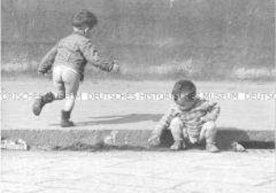 Zwei kleine, halbnackte Jungen spielen am Straßenrand
