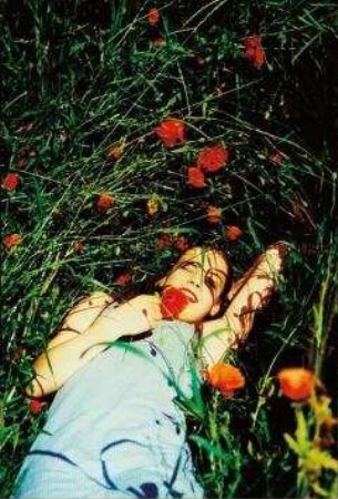 Junge Frau liegt in einer Wiese mit Mohnblumen (Altersgruppe 18-21)
