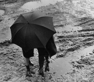 Tauwetter und es regnet. Überall Pfützen. Ein Paar unter einem Regenschirm