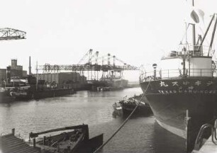 Hamburg, Hafen : Hamburg. Hafen. Hafenbecken mit Umschlagplätzen Kai/Schiff und Seeschiff/Binnenschiff. Blick auf einem Kai mit Portalkränen , im Vordergrund Heck eines japanischen Frachters