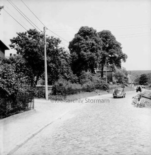 Groß Barnitz: Dorfstraße mit Kopfsteinpflaster: hinten rechts VW-Käfer und Trecker: links Strommasten: dahinter Häuser und Bäume