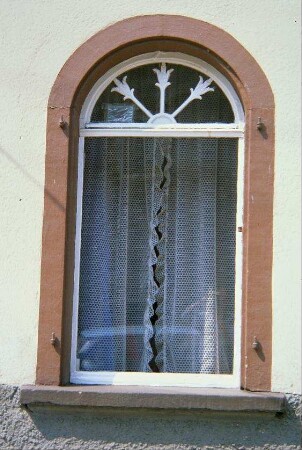 Fenster mit Rundbogen und Blumenmotiven in den Sprossen des Oberlichts