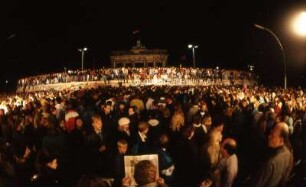 Berlin, 10. November 1989, auf der Mauer am Brandenburger Tor tanzen die Menschen