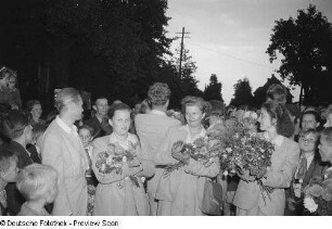 Applaudierende Frauen mit Blumensträußen im Arm bei einer Veranstaltung am Tag der Republik