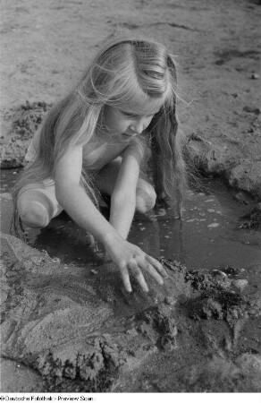 Mädchen, mit Sand spielend