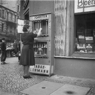 Berlin. Tabakwarengeschäft Lehmann. Besitzerin bestückt einen Zigarettenautomaten vor dem Geschäft