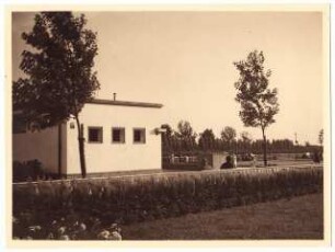 Spielplatz, Hindenburg: Rasenfläche mit Randbepflanzung, im Hintergrund Cafe (Milchhalle) mit angrenzendem Wasserbecken. Spielplatz an der Sosnitzaer Straße