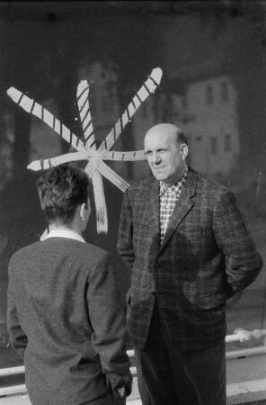 Niesky. Zwei Männer stehen vor einem Schaufenster, dessen Scheibe mit einem Farbkreuz markiert ist, und unterhalten sich