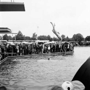 Sommerbad Tarpenbek: Am Hallenbad: Eröffnung: Person springt vom Sprungturm, Gäste am Rand des Schwimmbeckens