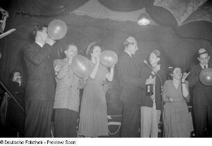 Gäste beim Aufblasen von Luftballons