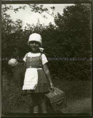 Kleines Mädchen mit Korb und Puppe