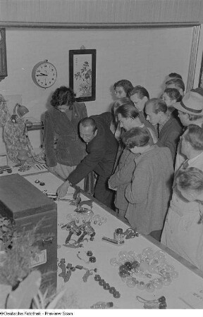 Besucher an einem Messestand mit chinesischen Ausstellungsobjekten (Lampen, Bügeleisen, elektrische Geräte)