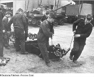 Goldberg (Kreis Lübz). Nationale Volksarmee - Landstreitkräfte. Panzerregiment 8 (PR-8). Freifläche vor Panzerhallen. Soldaten bei Instandsetzungs- bzw. Wartungsarbeiten an Gleisketten für Kampfpanzer T-54