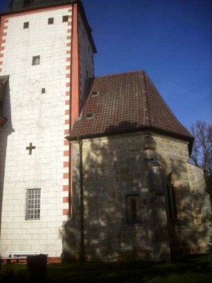 Kirchturm von Süden (Romanisch um Jahr 1200) mit Kreuzschlitzscharte (Schießscharte für Armbrust) im Mittelgeschoss über Chorraum (Fenster neuzeitlich verändert)